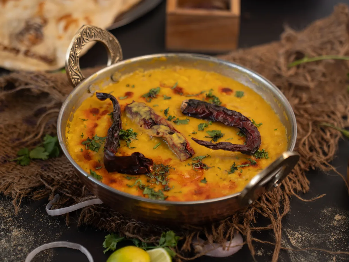 Yellow dal with dried red chillies in a small metal kadai