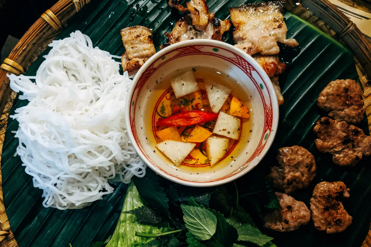 Bun cha on a banana leaf: grilled pork, rice noodles and a bowl of fish sauce dipping sauce with chilli