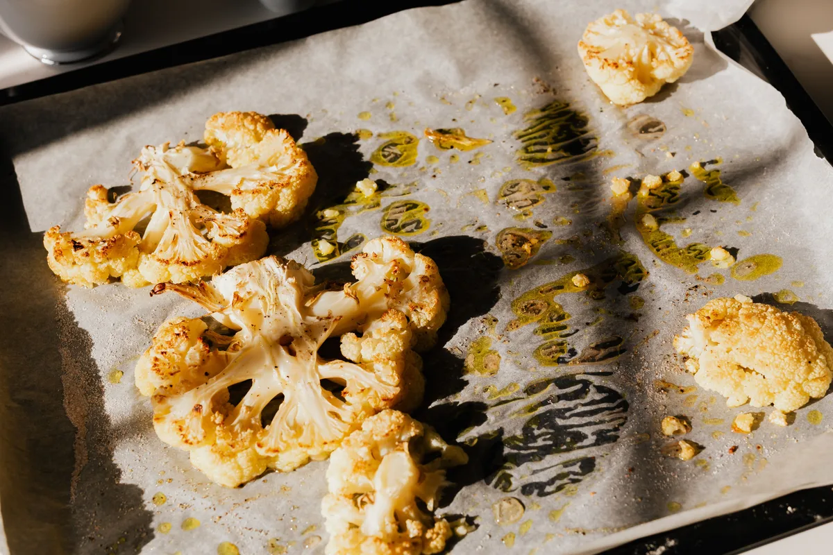 Roasted cauliflower florets on a parchment-lined baking tray