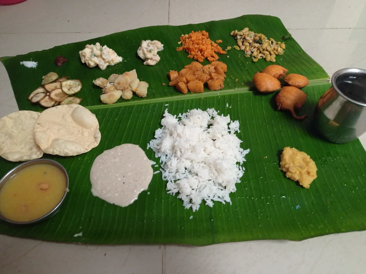 A South Indian meal on a banana leaf: rice at the centre, with dal, papads, fried snacks and small vegetable sides