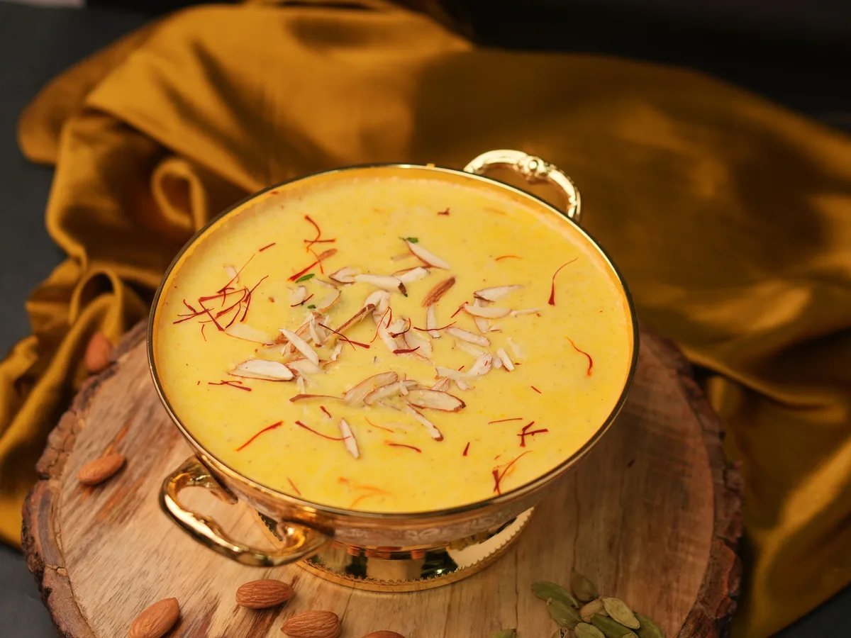 Kesar phirni, a saffron and ground-rice milk pudding, in a golden bowl topped with sliced almonds