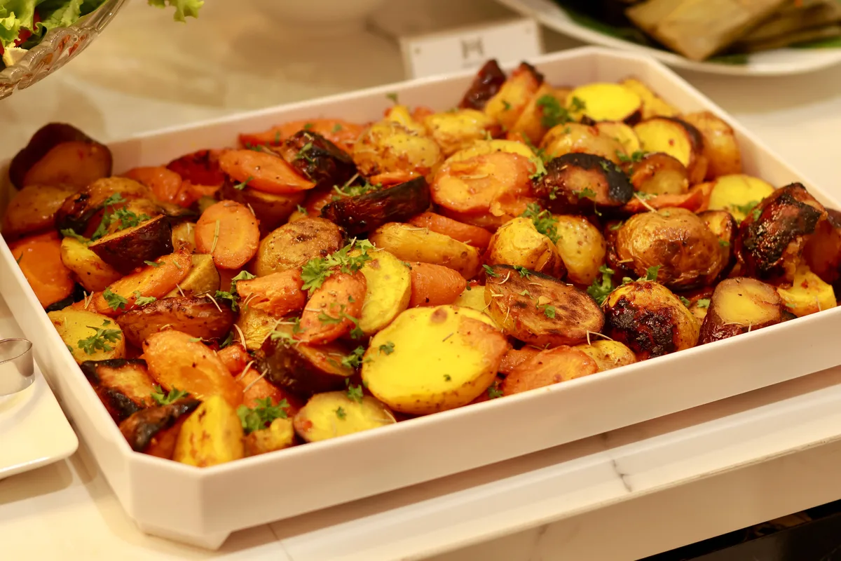 A tray of roasted root vegetables scattered with herbs