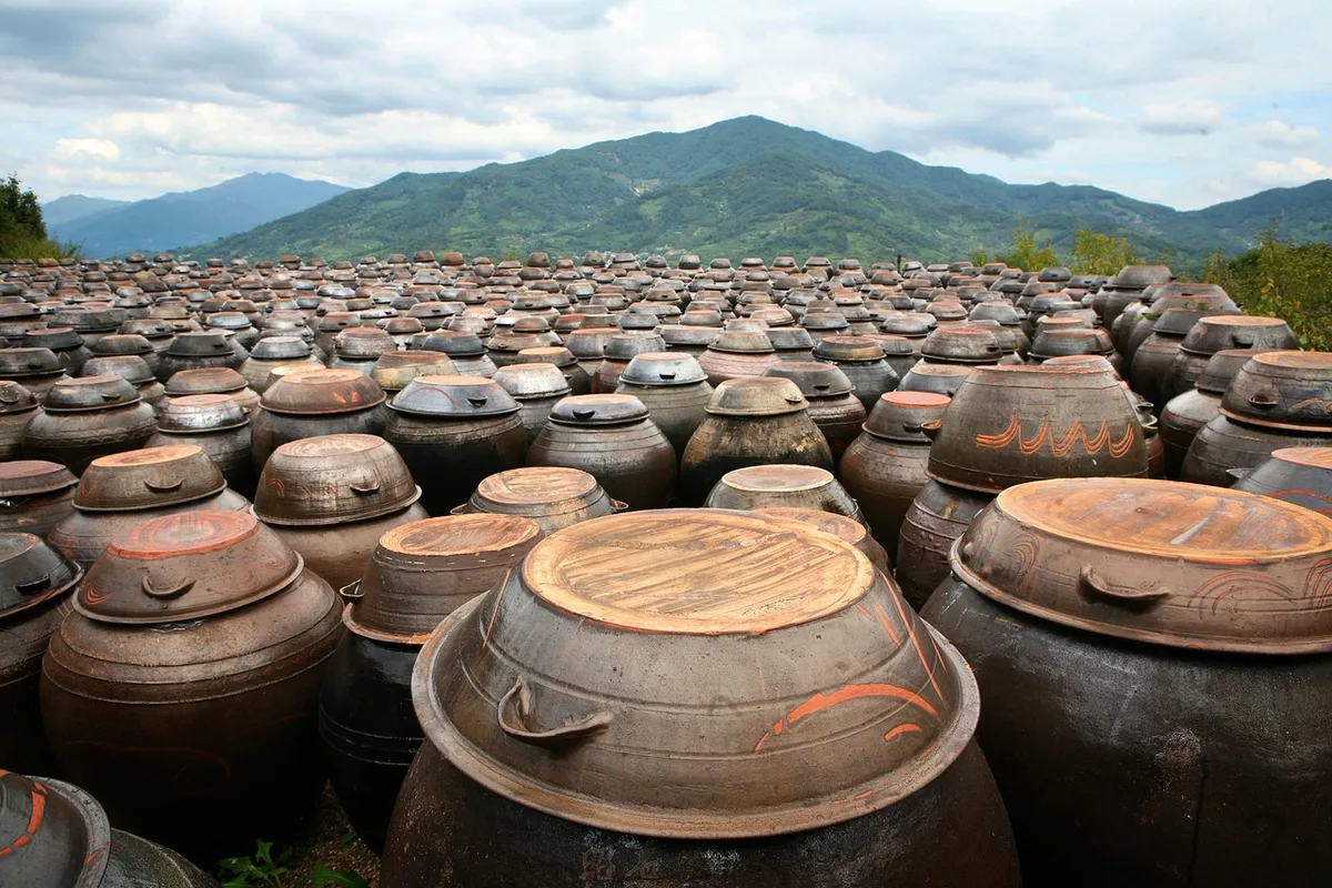 Rows of lidded onggi crocks on a jangdokdae, with mountains behind