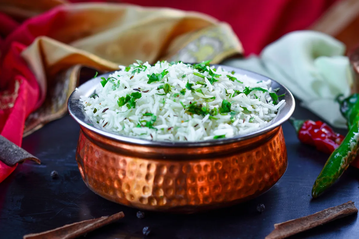 Rice with cumin seeds and chopped cilantro in a hammered copper bowl