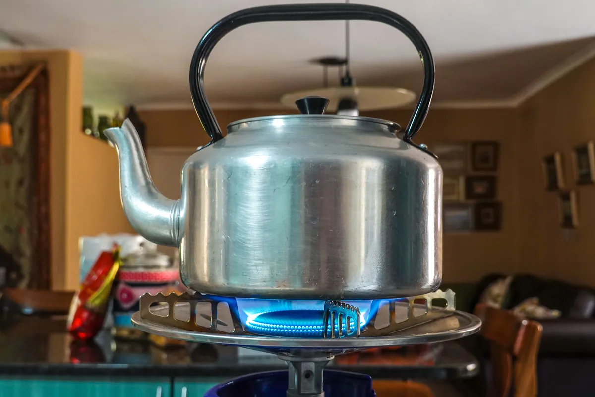 An aluminum kettle heating on a gas burner